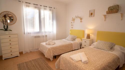 een slaapkamer met twee bedden, een ladekast en een raam bij Villa Cal Peso in Port de Pollença