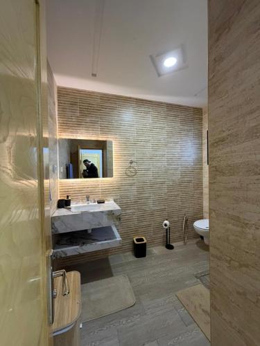a bathroom with a sink and a mirror and a toilet at Montaseur s3 in Al Maqārisah