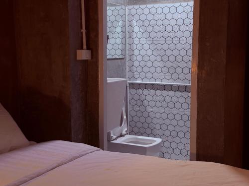 a bathroom with a toilet next to a bed at WSTAR Hostel in Bangkok