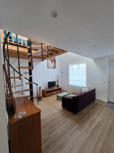 a living room with a staircase and a couch at La maison de l'orée de la forêt in Hasnon