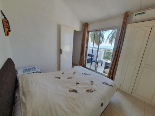 a bedroom with a bed with a view of the ocean at Villa de la Plage sous les cocotiers in Saly Portudal