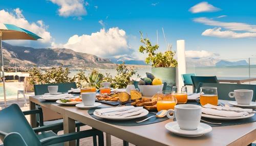 a table with food and drinks and a view of the ocean at Hotel La Battigia in Alcamo Marina