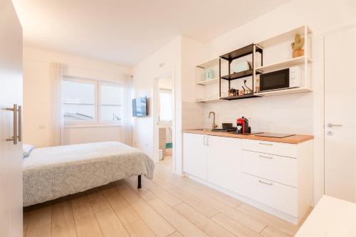 a white room with a bed and a kitchen at Conca d'Oro Apartments, camera 1 e 2 in Nago-Torbole