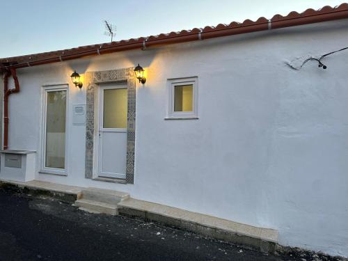 een wit huis met twee ramen en een deur bij Refúgio do Ribeirinho in Paredes de Coura