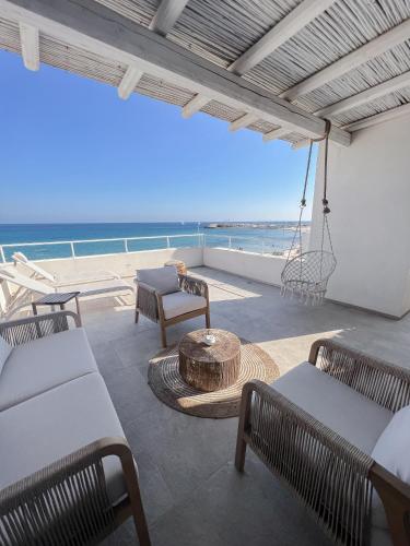 a patio with chairs and a swing and the ocean at Palma Residence Salento in San Foca