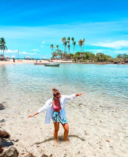 a woman standing on a beach with her arms outstretched at Encantos do Morro in Cairu