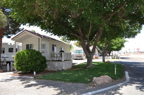 a small house with a porch and a tree at Las Vegas Camping Resort Cabin 3 in Las Vegas
