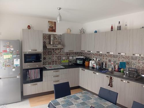 a kitchen with white cabinets and a refrigerator at D-Onyx Holiday lets Apartment in Żebbuġ