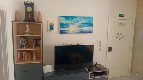 a living room with a flat screen tv and a clock at D-Onyx Holiday lets Apartment in Żebbuġ