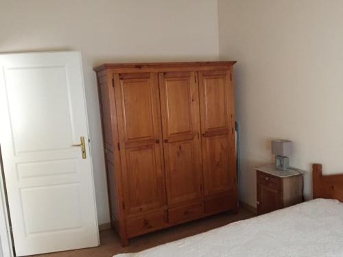 een slaapkamer met een houten kast naast een bed bij Maison calme et agréable proche de la mer in Saint-Gervais