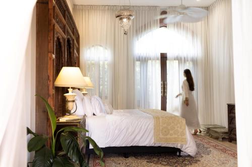 ein Schlafzimmer mit einem Bett und eine Frau am Fenster in der Unterkunft Jodha Bai Retreat in Terranora