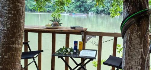 a table and chairs on a deck with a view of a river at Papaya Resort Nong Khiaw in Nongkhiaw