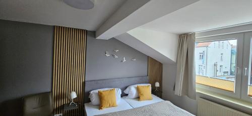 une chambre avec un lit avec des oreillers jaunes et une fenêtre dans l'établissement Gasthaus Harmonie, à Malchow