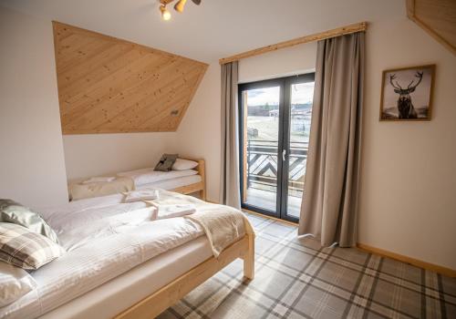 a bedroom with a bed and a window at Domki Tomanova - Premium Chalets in Dzianisz