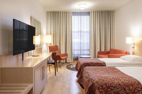 a hotel room with two beds and a flat screen tv at Scandic Oulu City in Oulu