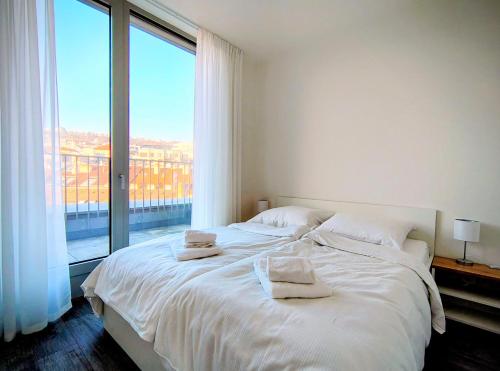 a bedroom with a white bed with a large window at MamaStay Andel Apartments in Prague