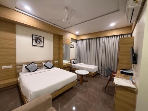 a hotel room with two beds and a television at Hotel Krish villa in Vadodara