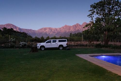 un camion blanc garé dans une cour avec des montagnes en arrière-plan dans l'établissement De Hoop Farm - mountain view, à Breërivier