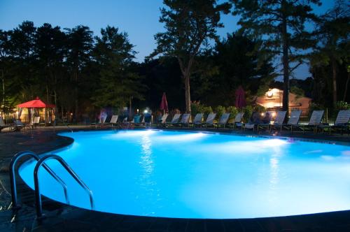 een groot zwembad met blauwe verlichting in de nacht bij Sea Pines Loft Park Model 3 in Swainton