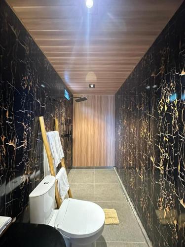 een badkamer met een toilet en een zwarte muur bij Sai Wana Cabin Bedugul in Bedugul
