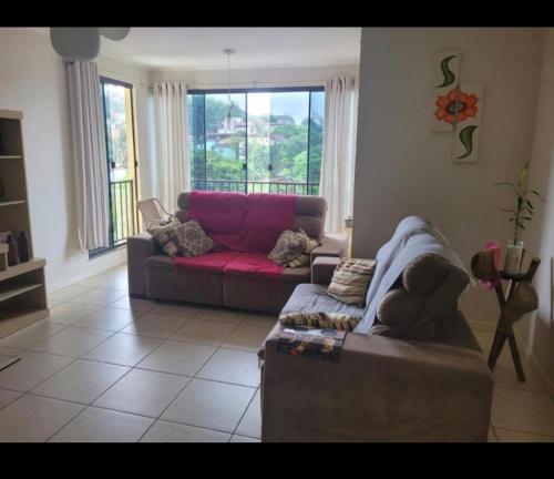a living room with a red couch in front of a window at apto para 2 pessoas in Santa Rosa