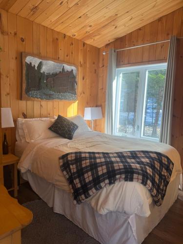 ein Schlafzimmer mit einem großen Bett mit Fenster in der Unterkunft Le Richelieu in St-Bernard de Lacolle