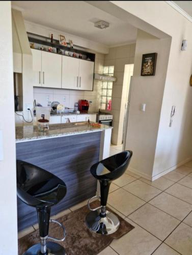 a kitchen with two black bar stools in front of a counter at apto para 2 pessoas in Santa Rosa