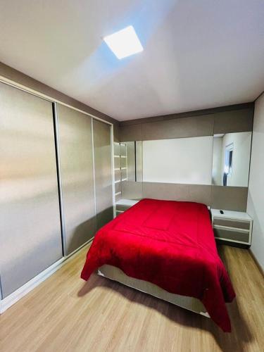 a bedroom with a red bed with a red blanket at Casa condomínio lagoa cortada in Balneário Gaivotas