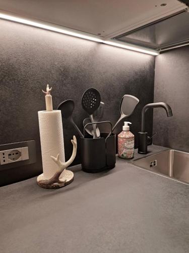 a kitchen counter with a sink and some utensils at VHĀUS Apartment and Spa in Predazzo