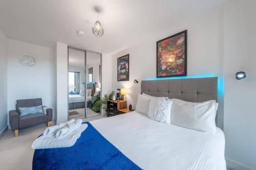 a bedroom with a large white bed with a blue blanket at Stylish 1-Bed Apt in Harrow with Balcony near Heathrow and Wembley in Harrow