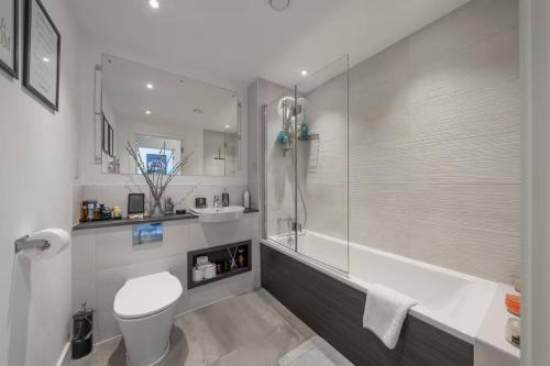 a bathroom with a tub and a toilet and a sink at Stylish 1-Bed Apt in Harrow with Balcony near Heathrow and Wembley in Harrow