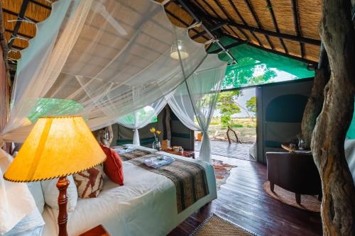 una camera da letto con un letto a baldacchino con una lampada di Camp Silwane 