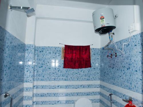 a bathroom with blue tiled walls and a red curtain at Silverberry Homestay in Rishop