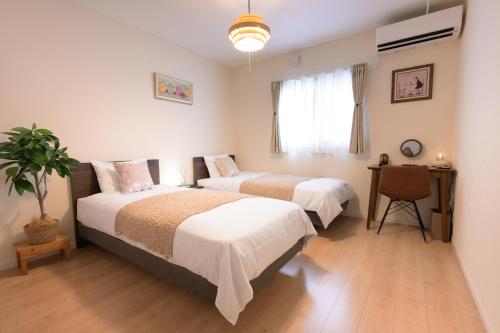 a bedroom with two beds and a desk with a plant at tazuraya-ritsurin-一棟貸切-無料駐車場 in Takamatsu