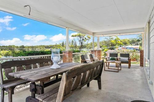 a patio with a wooden table and benches on a balcony at Neptune's at Manyana in Manyana