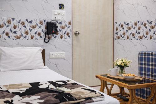 a bedroom with a bed and a table with a bowl of flowers at Relax Hotel Kurla in Mumbai