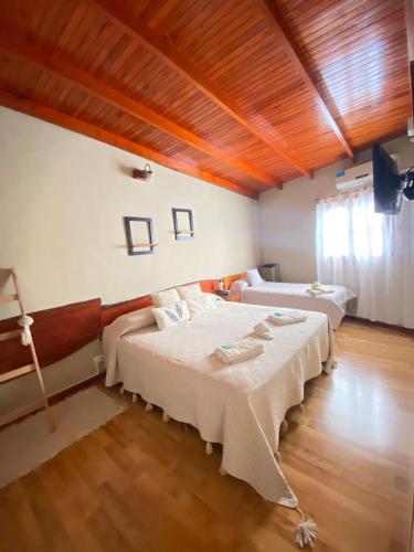 a bedroom with two beds and a wooden ceiling at Apart Hotel Rústicos Valentina in Dolores