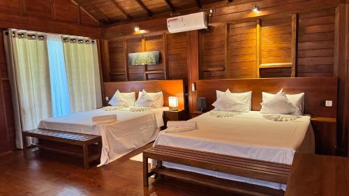 two beds in a room with wooden walls and wood floors at Ceylon Elegance Villa in Kurunegala