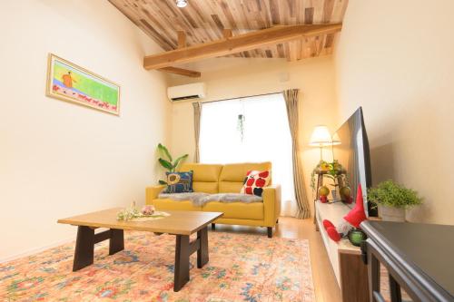 a living room with a yellow couch and a table at tazuraya-ritsurin-一棟貸切-無料駐車場 in Takamatsu
