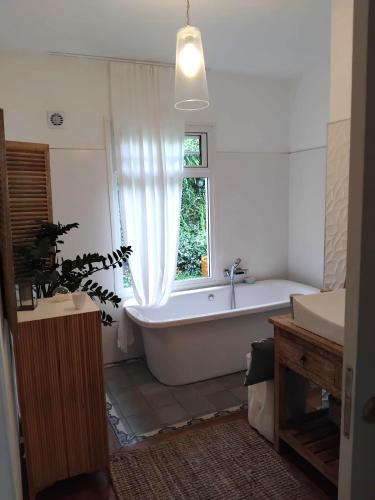 a white bathroom with a tub and a window at Les Fougères in Les Avirons