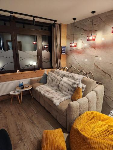 a living room with a couch and a stone wall at Zalona Altitude Appartement T3 - Emplacement exceptionnel - entrée indépendante - entièrement rénové in Tignes