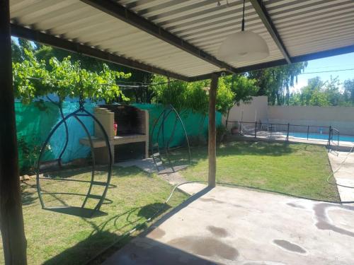 een pergola met een tafel en stoelen in een tuin bij Complejo Cabañas del Cristo in San Rafael