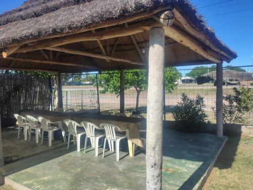 een tafel en stoelen onder een rieten dak bij Complejo Cabañas del Cristo in San Rafael