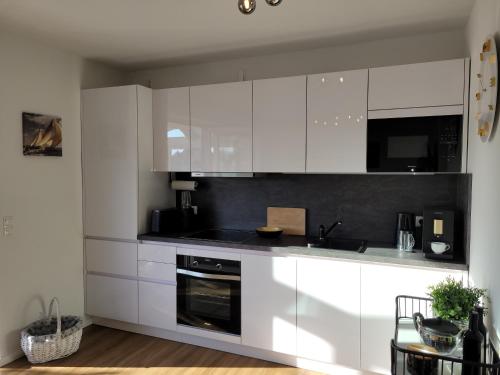 a kitchen with white cabinets and a black counter top at Sonneninsel Wiek mit eigener Sauna und Fahrradgarage inkl Wäschepaket in Wiek auf Rügen