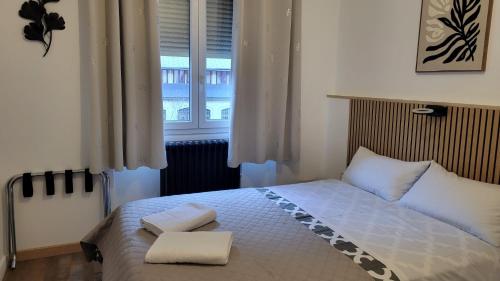 a bedroom with a bed with two pillows and a window at hotel de la gare in Modane