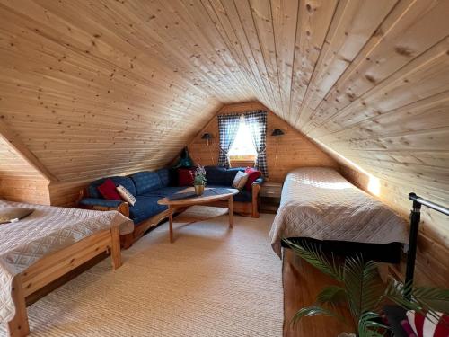 ein Zimmer mit 2 Betten und einem Sofa in einem Blockhaus in der Unterkunft Cozy Mountain Cabin in Senja in Senja