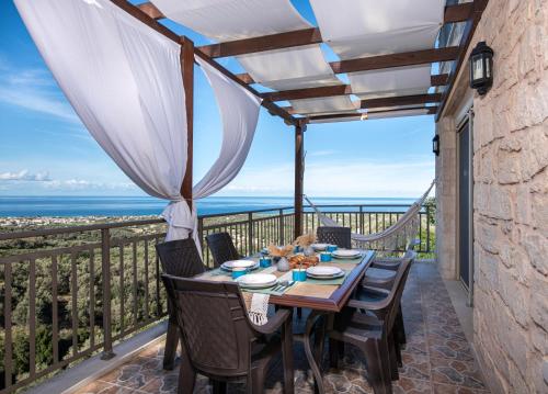 a dining table on a balcony with a view of the ocean at Great Escape Sea View Private Pools, Jacuzzi & Ultimate Relaxation in Maroulás