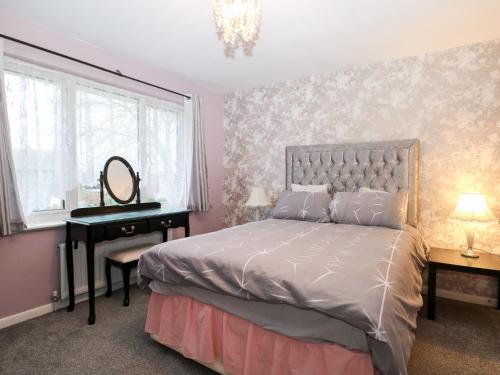 a bedroom with a bed and a desk and a mirror at Green Bank in Dymchurch