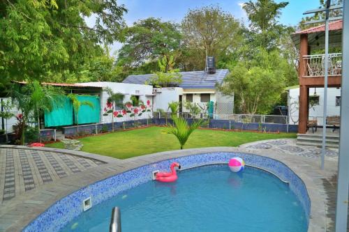 a swimming pool with pink swans in a yard at Arpan Villa in Aurangabad