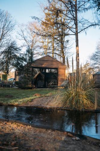 a wooden cabin with a pond in front of it at Holiday Home Maridu Wellness in Arnhem